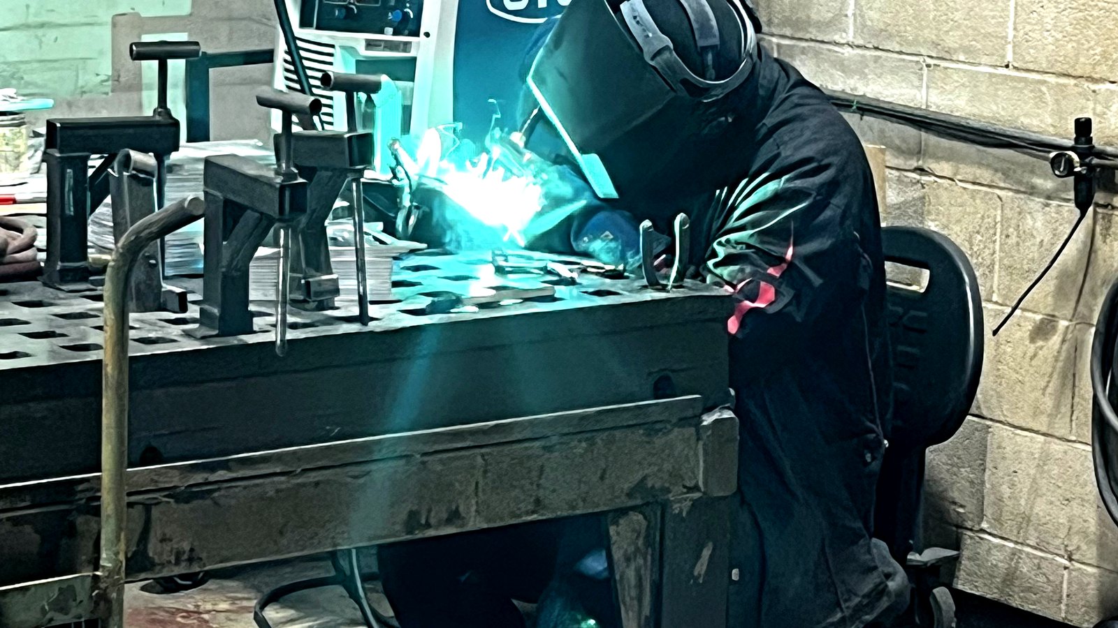 Welder joining sheet metal at a PCI fabrication table